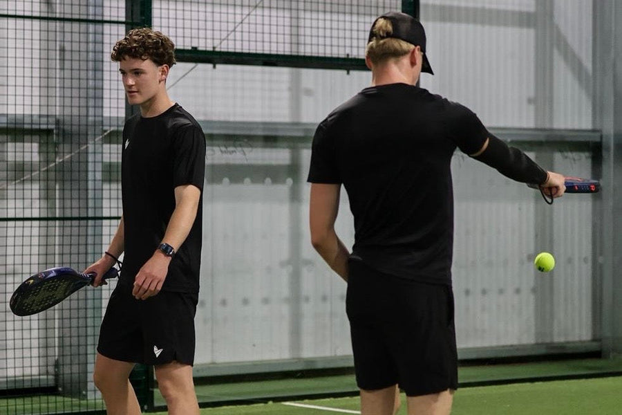 Two padel players on court wearing black performance clothing