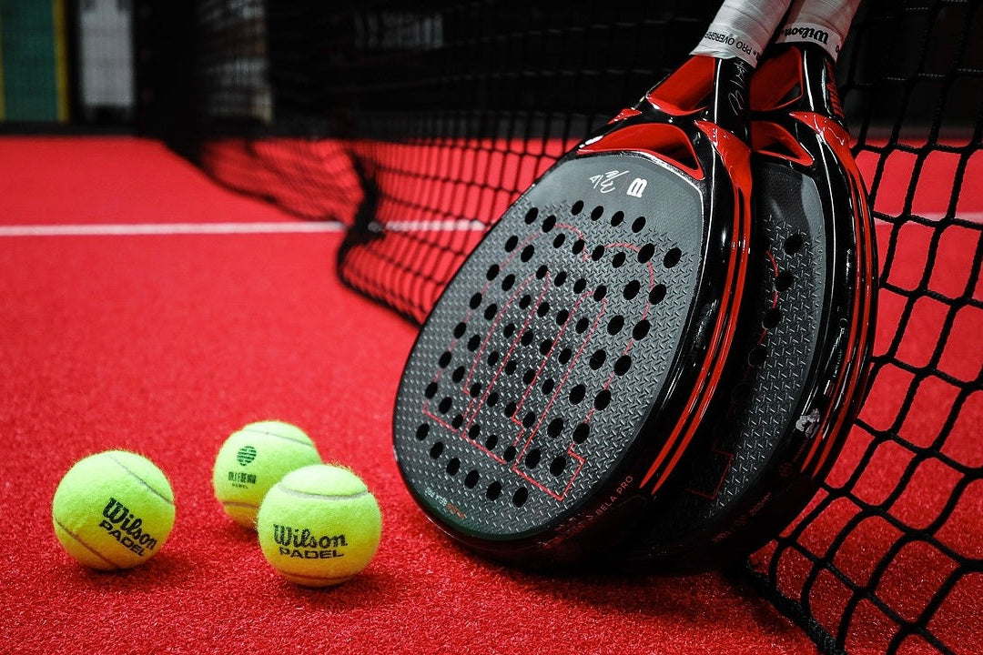 Padel racket and balls on a red padel court