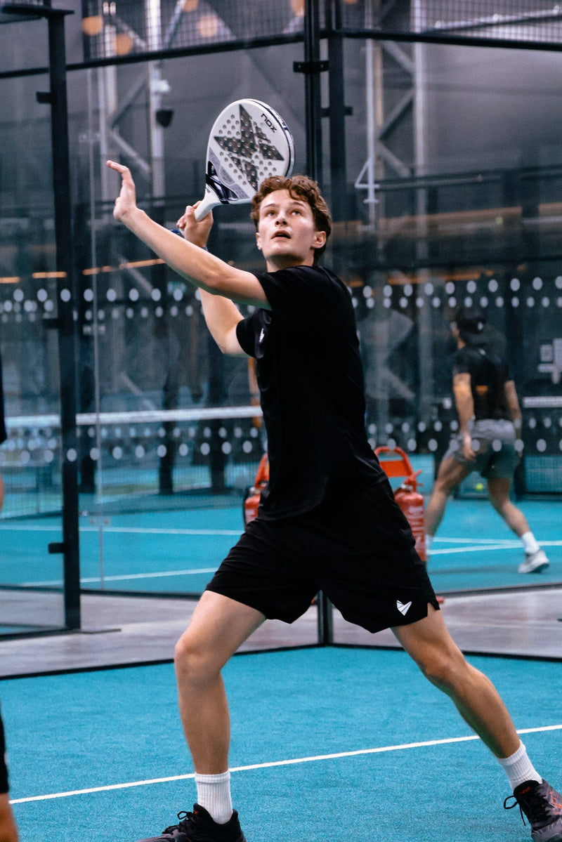 Padel Source Athlete Oscar Brand wearing the Padel Source Pro Performance 7 Inch shorts on court, lunging as he is about to hit a vibora.