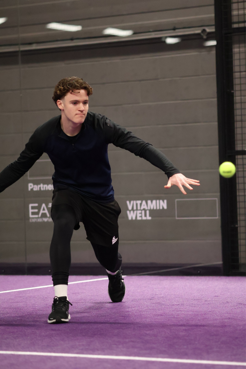 Luke Towler lunging for a padel forehand on a purple court while wearing comfortable, breathable padel clothes.