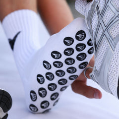 Person wearing a Pro Performance Padel sock with black patterns and a grey athletic shoe.
