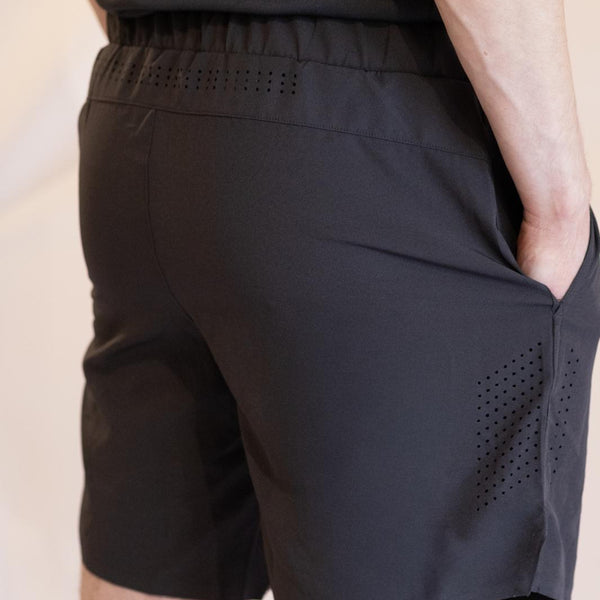 Black athletic shorts with perforated ventilation design on a neutral background