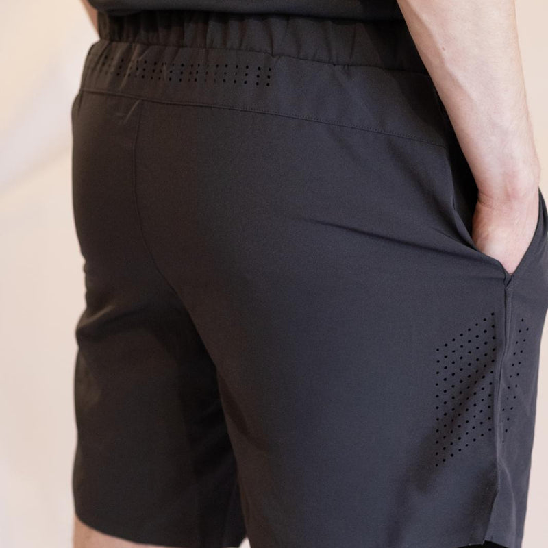 Black athletic shorts with perforated ventilation design on a neutral background