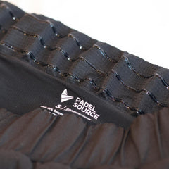 Black athletic shorts with a white logo on a neutral background